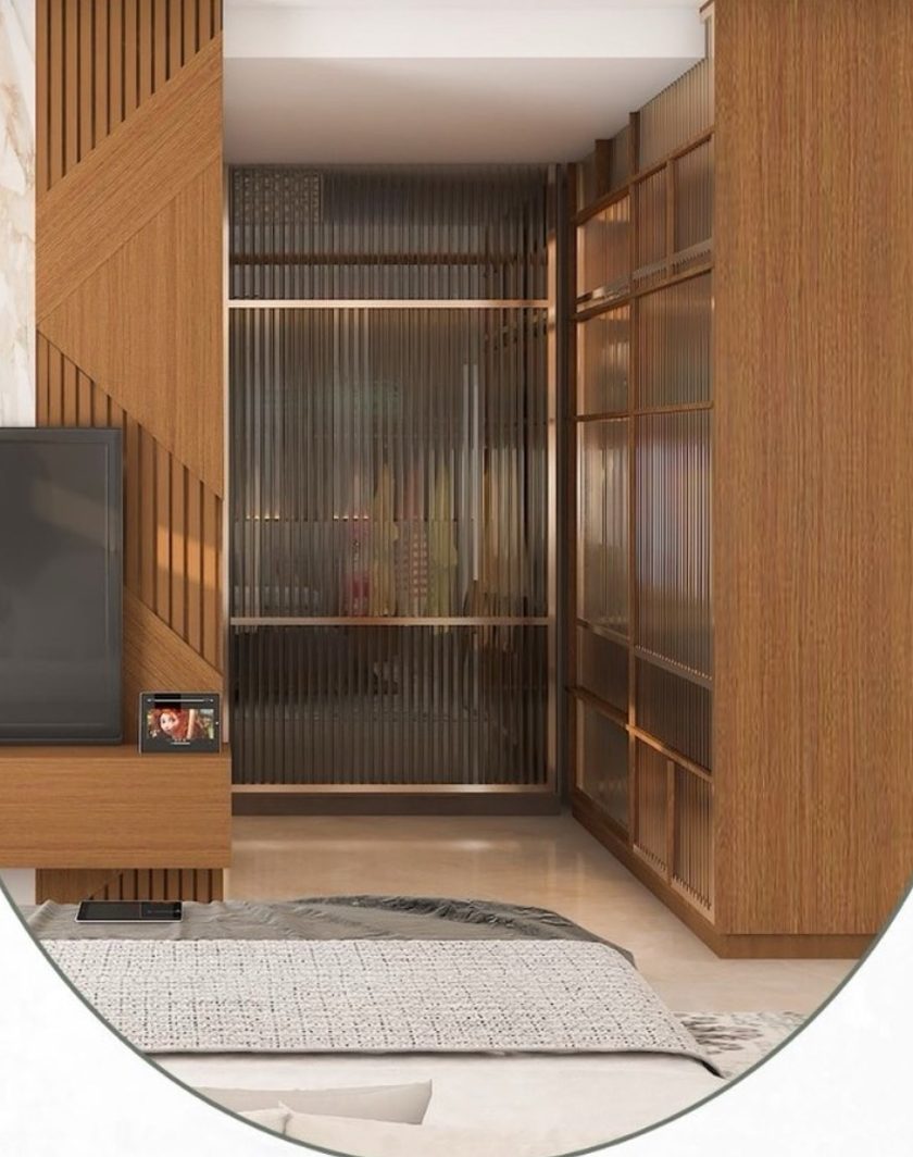 A bedroom wall with a wood-slatted TV unit and a walk-in wardrobe behind fluted glass